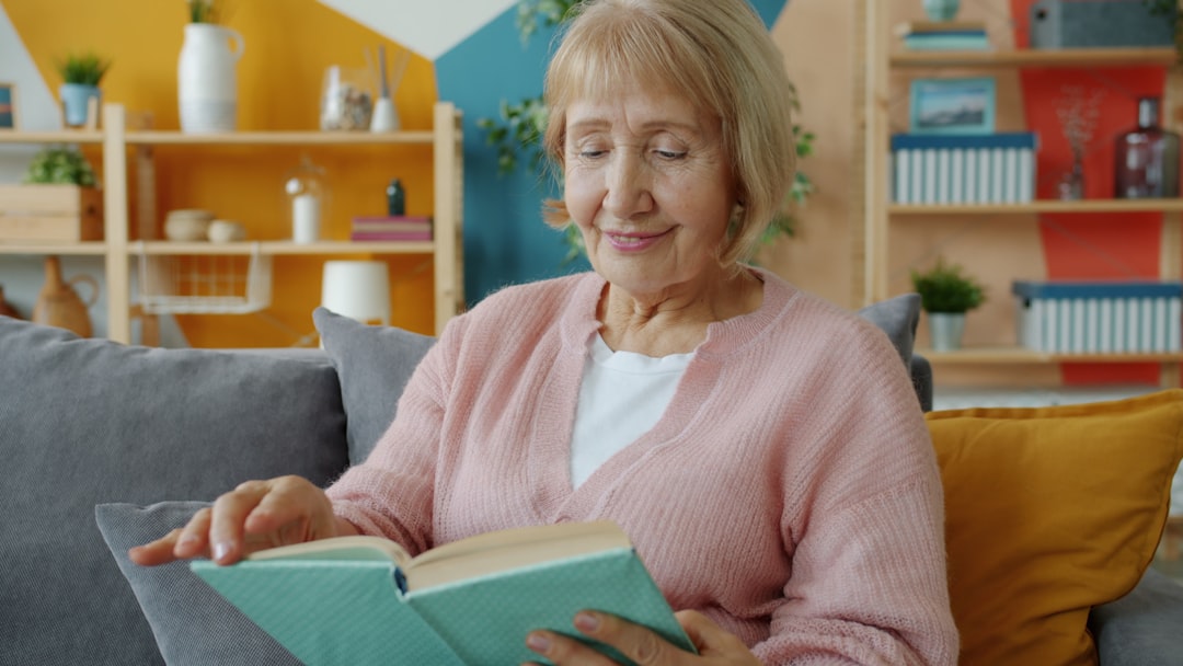 Elderly woman reading comfortably at home, illustrating calm elder care monitoring with Beside Care